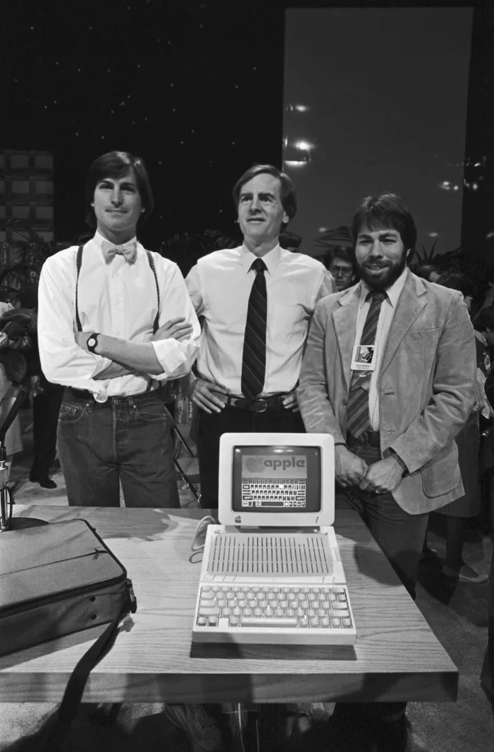 Стив Джобс, Джон Скалли и Стив Возняк улыбаются за компьютером Apple